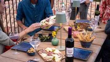 Una mesa de madera con diversos alimentos, como queso, pan y una botella de vino, lo que sugiere un ambiente de comedor informal.