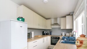 A modern kitchen with white cabinets, a built-in oven, a sink, and a coffee maker. - 3 Whin Bank (Oban)