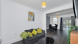 A modern living room with a grey sofa, a black coffee table, and a yellow pendant light.