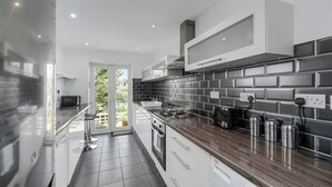 A modern kitchen with a dark tiled backsplash, stainless steel appliances, and a wooden countertop.