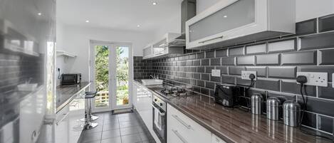 A modern kitchen with a dark tiled backsplash, stainless steel appliances, and a wooden countertop.