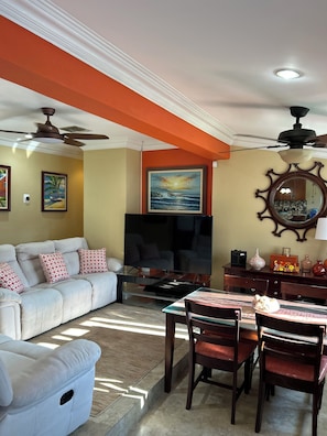 Relax in this stylish living room with a comfortable sofa, dining area, and large flat-screen TV.