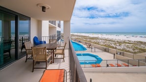 Een balkon met uitzicht op het strand, een zwembad en terrasmeubels.