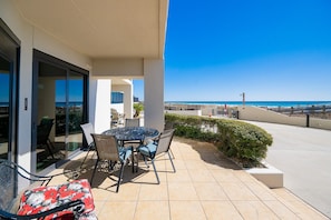 A patio with a table and chairs, a view of the beach, and a clear sky. - Phoenix Iii 3002 1 Bedroom Condo (Orange Beach)