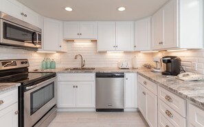 Fully equipped kitchen with microwave, oven, dishwasher, and coffee maker.
