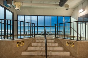 Stairs lead to an ocean view from a secure outdoor area with a bench.