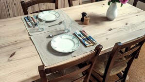 A dining table set with plates, cutlery, and a vase with flowers. - Gîte Prétanie - Pondside healthy lodging in lively Piégut-Pluviers (Piégut-Pluviers)