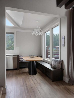 A compact kitchen with a round table, built-in bench seating, and large windows. - Saddle Ridge B5 3 Bedroom Townhouse (Big Sky)
