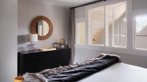 Un dormitorio con cama, cómoda, espejo y ventana con vista a una estructura de madera.