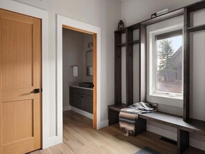 A room with a wooden door, a bench with a patterned throw, a window with a view, and a built-in shelf. - Saddle Ridge B5 3 Bedroom Townhouse (Big Sky)