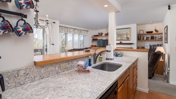 A modern kitchen with marble countertops, a built-in sink, and wooden cabinets. - 100 Snow Creek 2 Bedroom Condo (Warren)