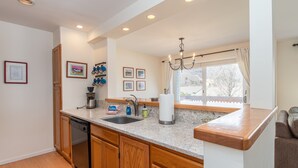 A kitchen with wooden cabinets, a dishwasher, a sink, and a window with a view. - 100 Snow Creek 2 Bedroom Condo (Warren)