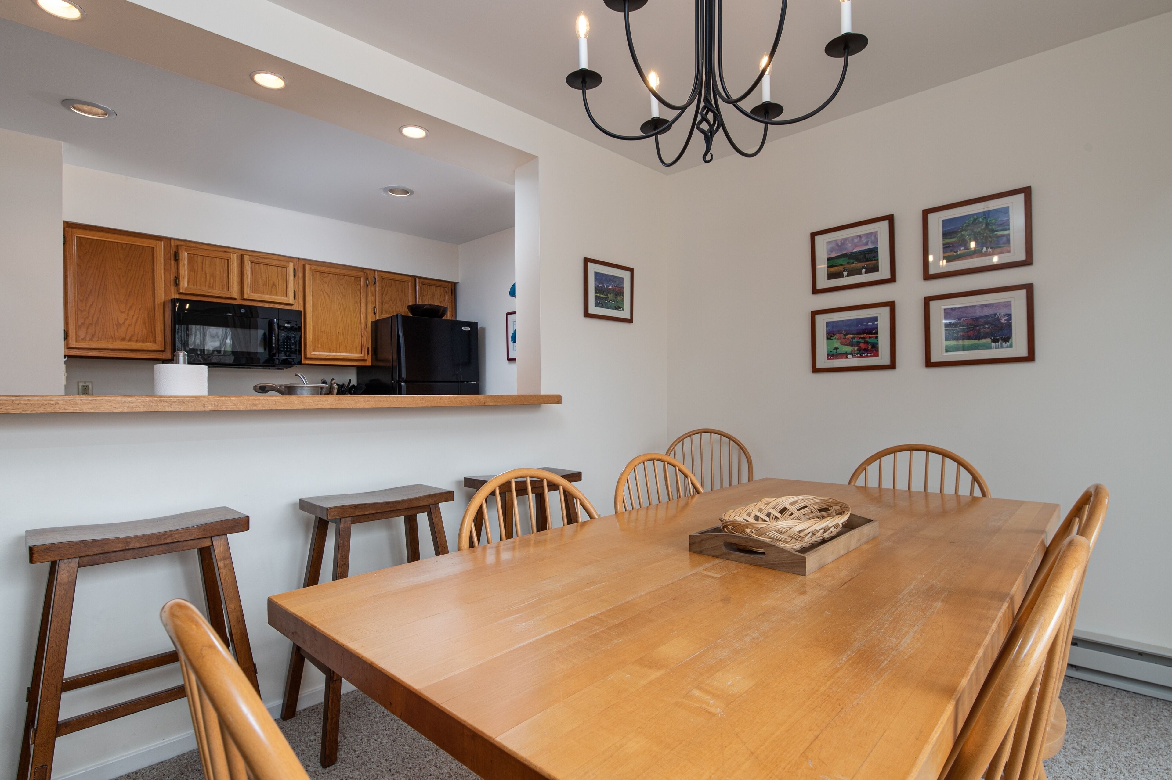 A dining area with a wooden table, chairs, and a chandelier.