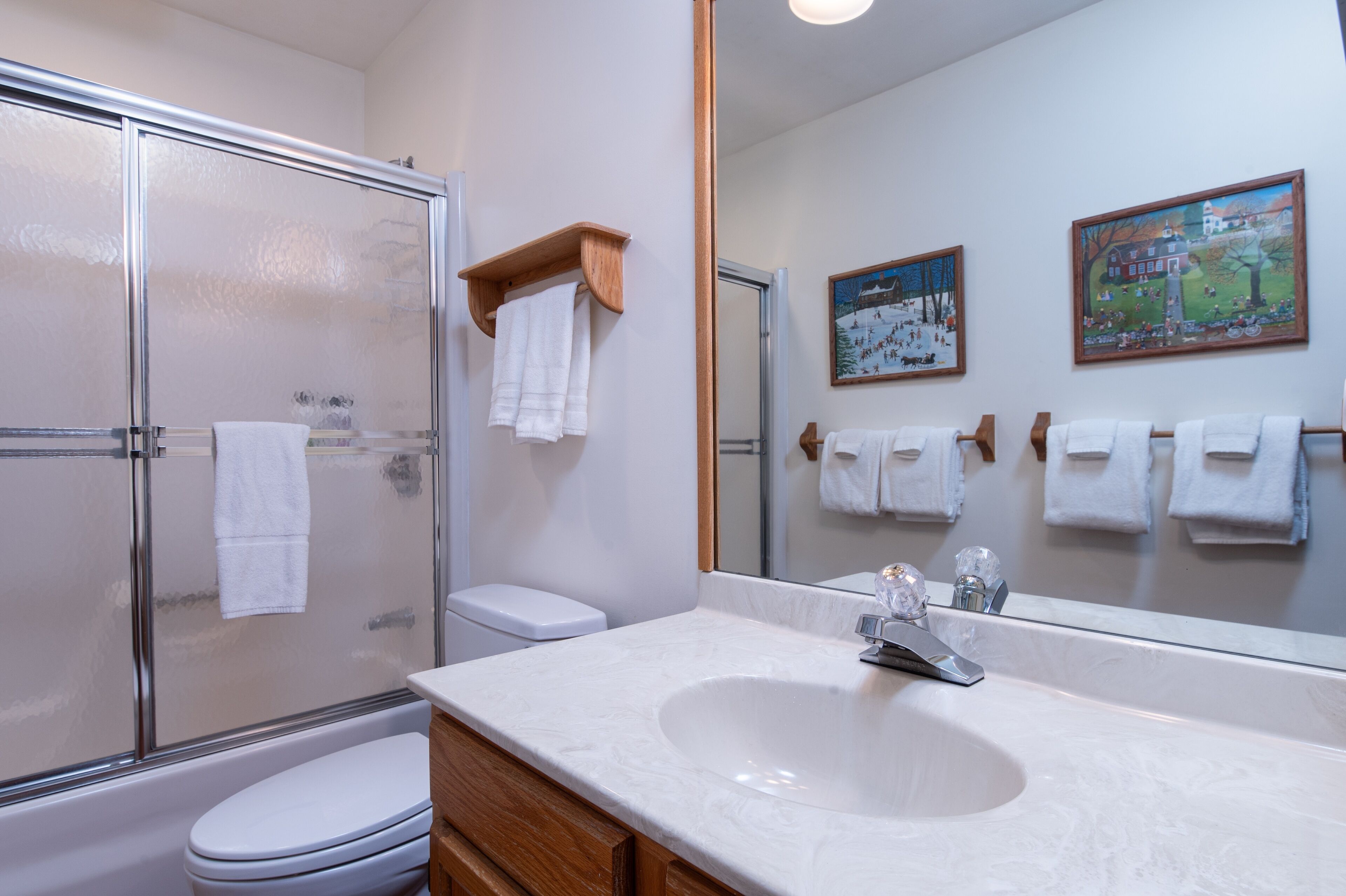 A bathroom with a glass-enclosed shower, a white sink, and a toilet.
