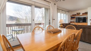 A dining area with a wooden table and chairs, a chandelier, and a view of the outdoors. - 100 Snow Creek 2 Bedroom Condo (Warren)