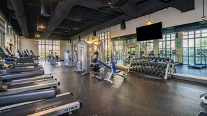 Uma academia espaçosa com esteiras, aparelhos de musculação e halteres.