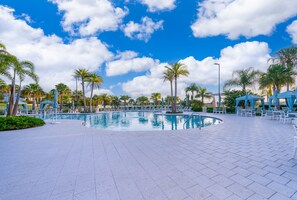 A swimming pool with lounge chairs and umbrellas, surrounded by palm trees and a clear sky. - New! Modern Townhome Near Disney! Splash Pool, Resort W/waterpark-8206sa 3 Bedroom Townhouse (Kissimmee)