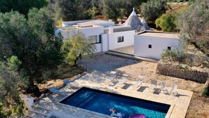 A modern villa with a swimming pool, outdoor seating, and a stone wall. - Il Trullo Delle Gemelle - Unforgettable stay in a villa with restored trullo (Provincia di Brindisi)