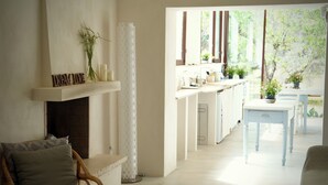 Een lichte, open woonkamer met een open haard, een eettafel met stoelen en uitzicht op groen.