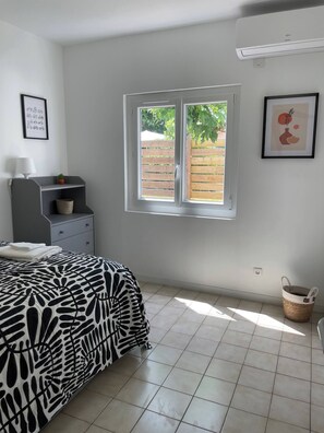 Una camera da letto con un letto, una scrivania, una sedia, una finestra vista sul verde e un condizionatore d'aria a parete.