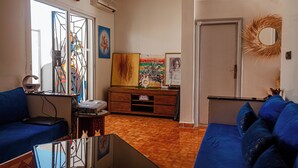 Ein Wohnzimmer mit einem blauen Sofa, einer Holzkabine und Kunstwerken an den Wänden.
