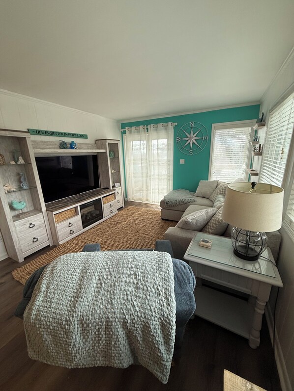 A cozy living room with a TV, sofa, and a lamp on a side table.