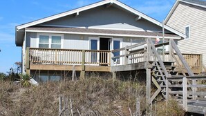 A two-story house with a wooden deck and a staircase leading to the second floor.