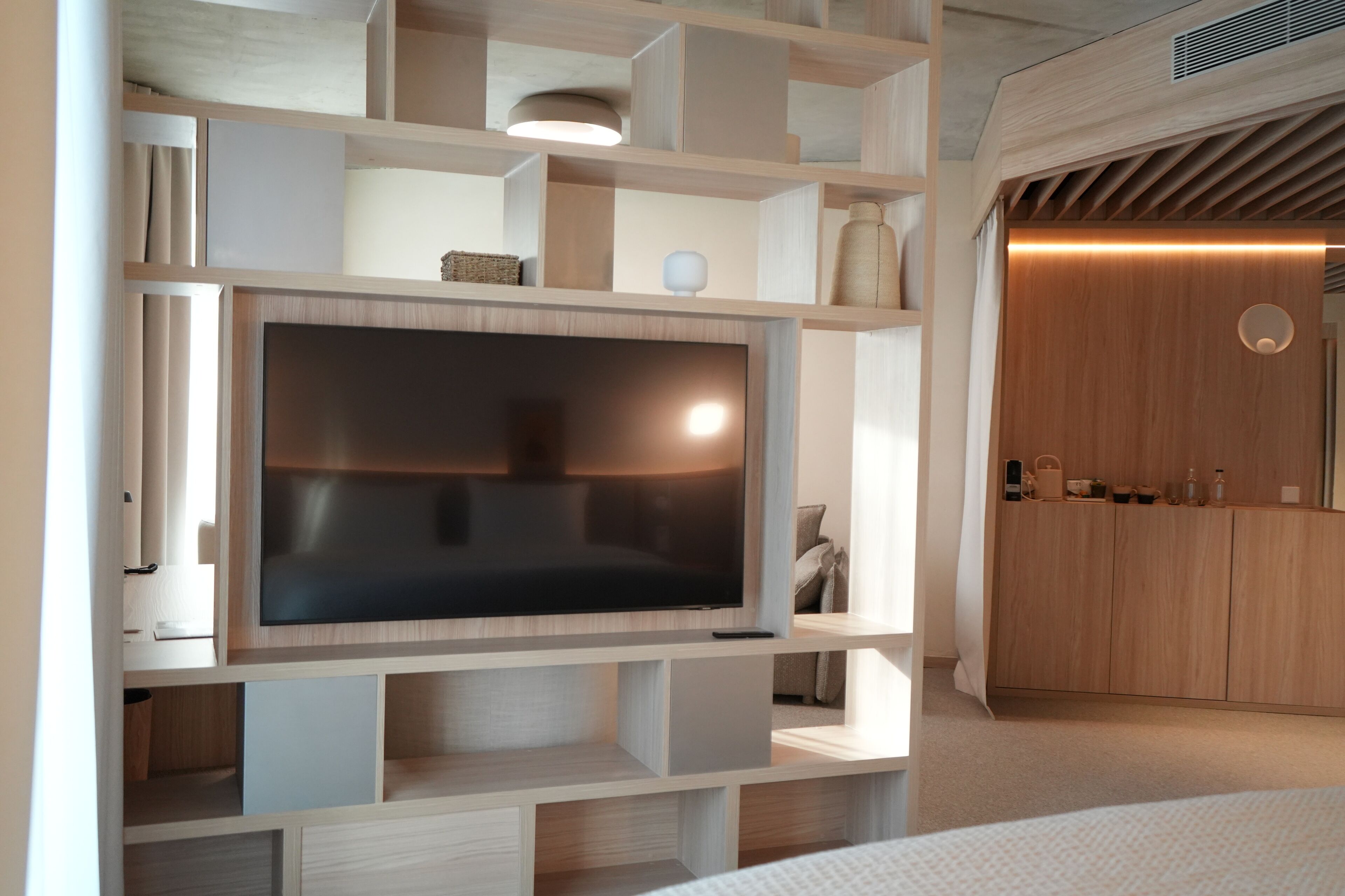 Un salon moderne doté d’un grand téléviseur à écran plat fixé sur un meuble mural en bois, de bibliothèques intégrées et d’un meuble en bois avec un miroir.