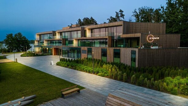 A modern hotel with a wooden facade, large windows, and a well-maintained outdoor area with a pathway and benches. - At Hotel 35 (Słupca)