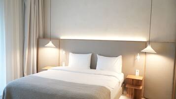 Ein modernes Hotelzimmer mit einem großen Bett, zwei Nachttischen und Pendelleuchten.