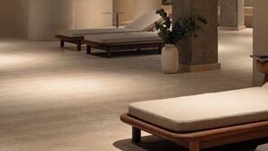 A modern spa area with wooden ceiling beams, lounge chairs, and a large pillar with a plant. - At Hotel 35 (Słupca)