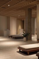 Uma área de spa moderna com vigas de madeira no teto, cadeiras de lounge e um grande pilar com planta.