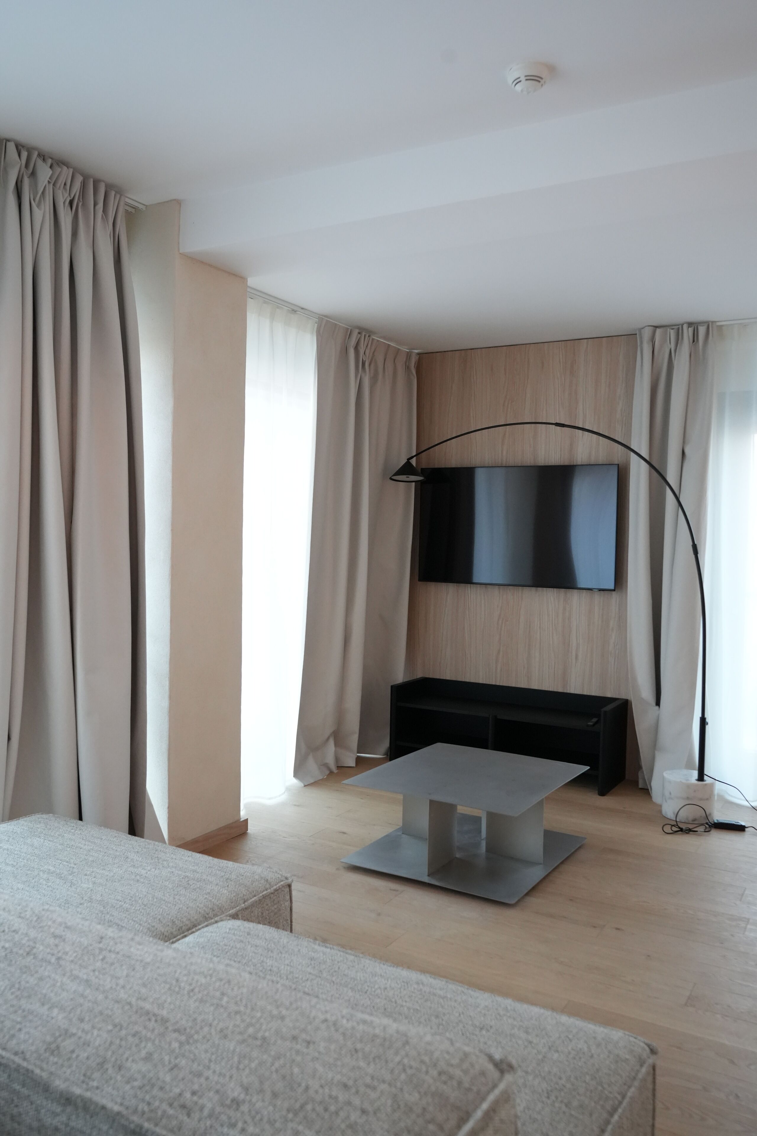 Uma sala de estar moderna com televisão de tela plana na parede, uma mesa de centro minimalista e um sofá.