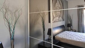 A modern bedroom with a large bed, a nightstand, a mirror, and decorative vases. - Aurelia Gozo BnB (Xaghra)
