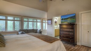 A bedroom with a large bed, a dresser, and a television on a stand.
