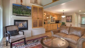 A living room with a fireplace, leather sofa, and a dining area with wooden cabinets.