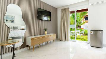Een moderne hotelkamer met een grote spiegel, een flatscreen televisie, een houten console tafel en een schuifpui naar een balkon.