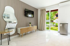 Una habitación de hotel moderna con un espejo grande, un televisor de pantalla plana, una mesa consola de madera y un gran ventanal corredero que da a un balcón.