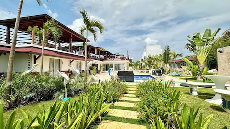 A resort with a pool, palm trees, and a covered outdoor area.