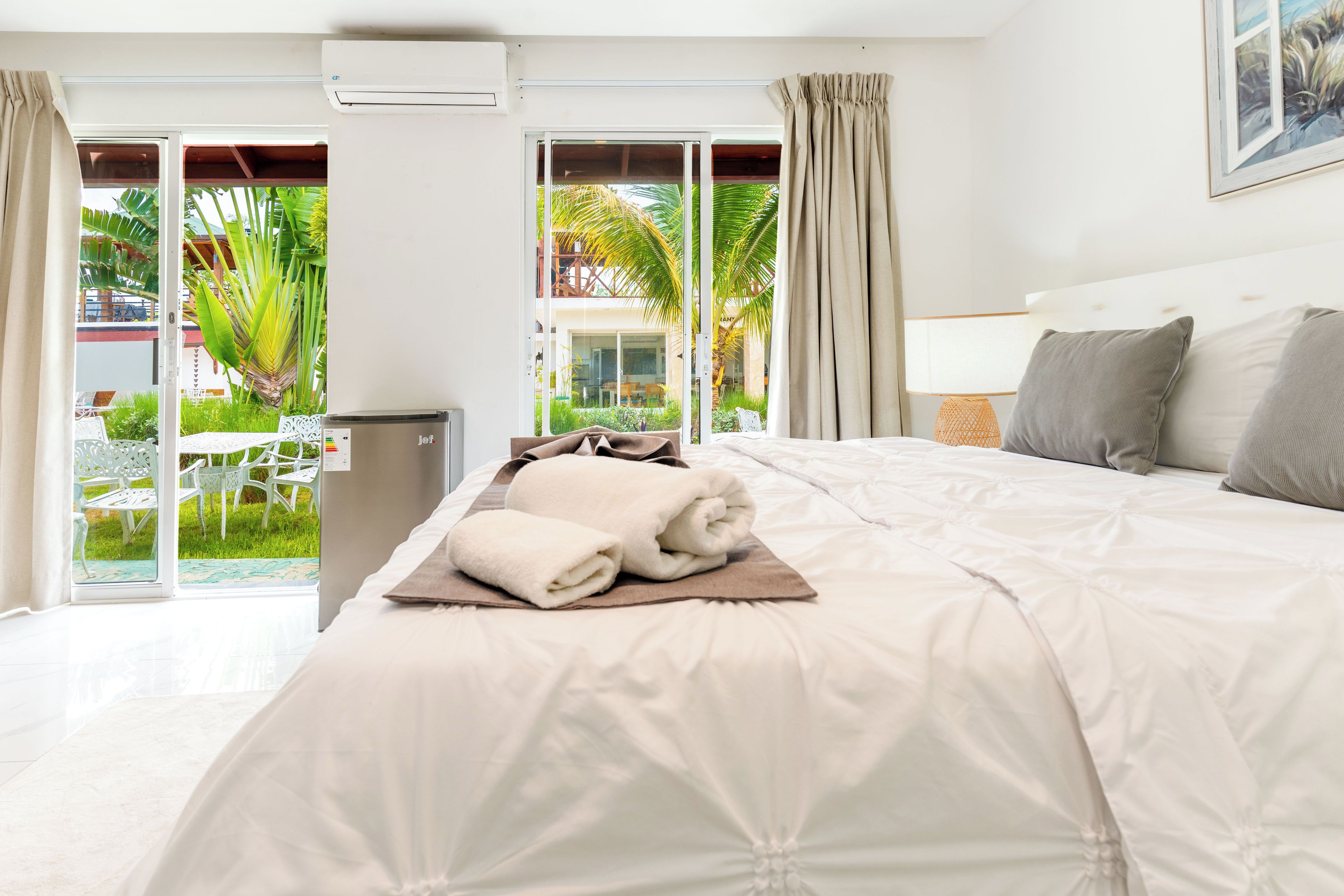 Habitación de hotel con cama, ventana con cortinas, equipo de aire acondicionado y vistas al exterior.