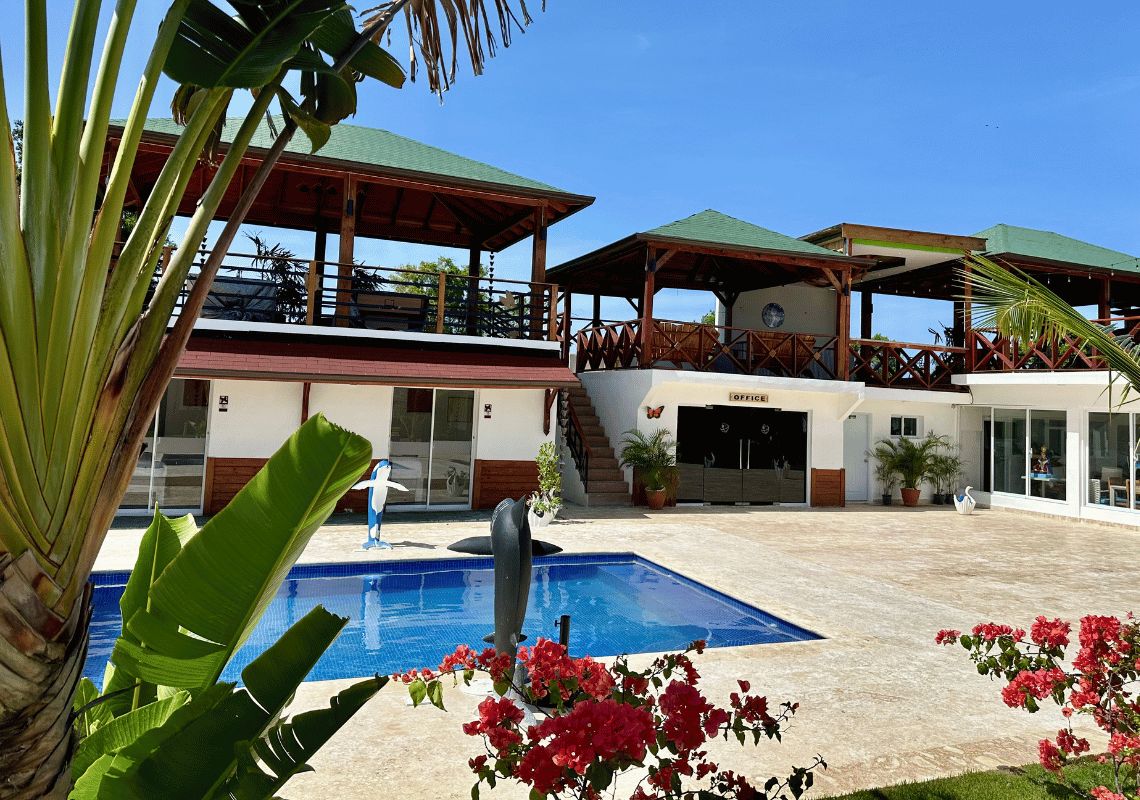 A hotel with a swimming pool, a dolphin sculpture, and a covered outdoor area.