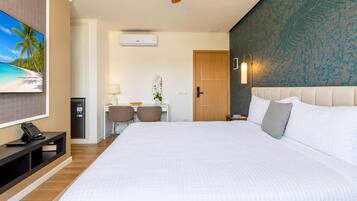 Una habitación de hotel con una cama grande, un escritorio con lámpara, un televisor y una puerta.