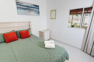 Ein Schlafzimmer mit einem Bett, einem Nachttisch, einem Fenster mit Vorhängen und einem Bild an der Wand.