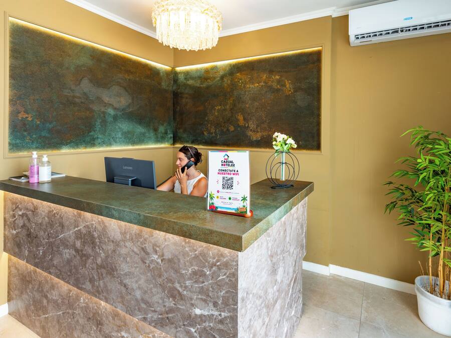 A hotel reception desk with a marble top, a sign offering free Wi-Fi, and a potted plant.
