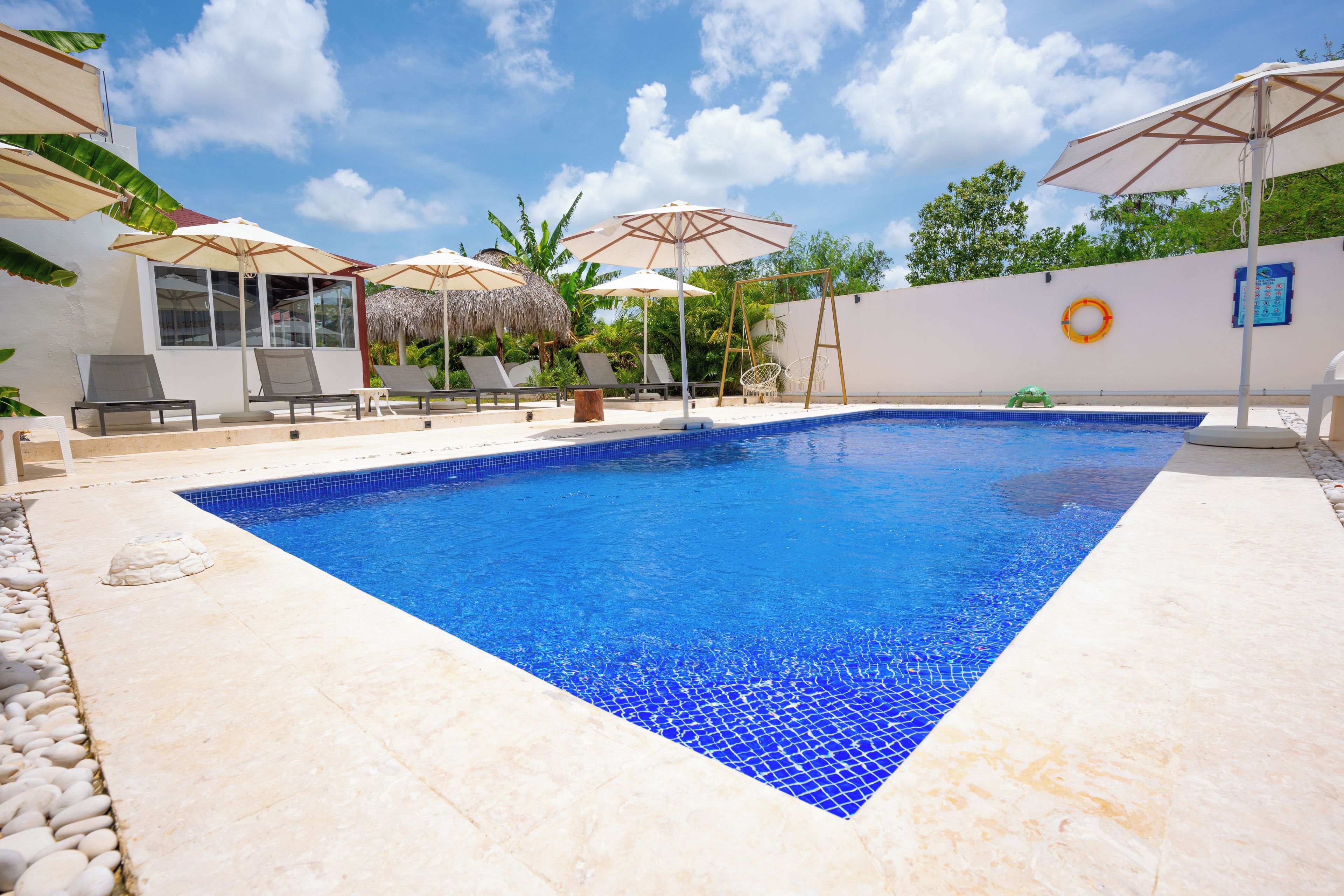 A swimming pool with a tiled edge, surrounded by lounge chairs and umbrellas.