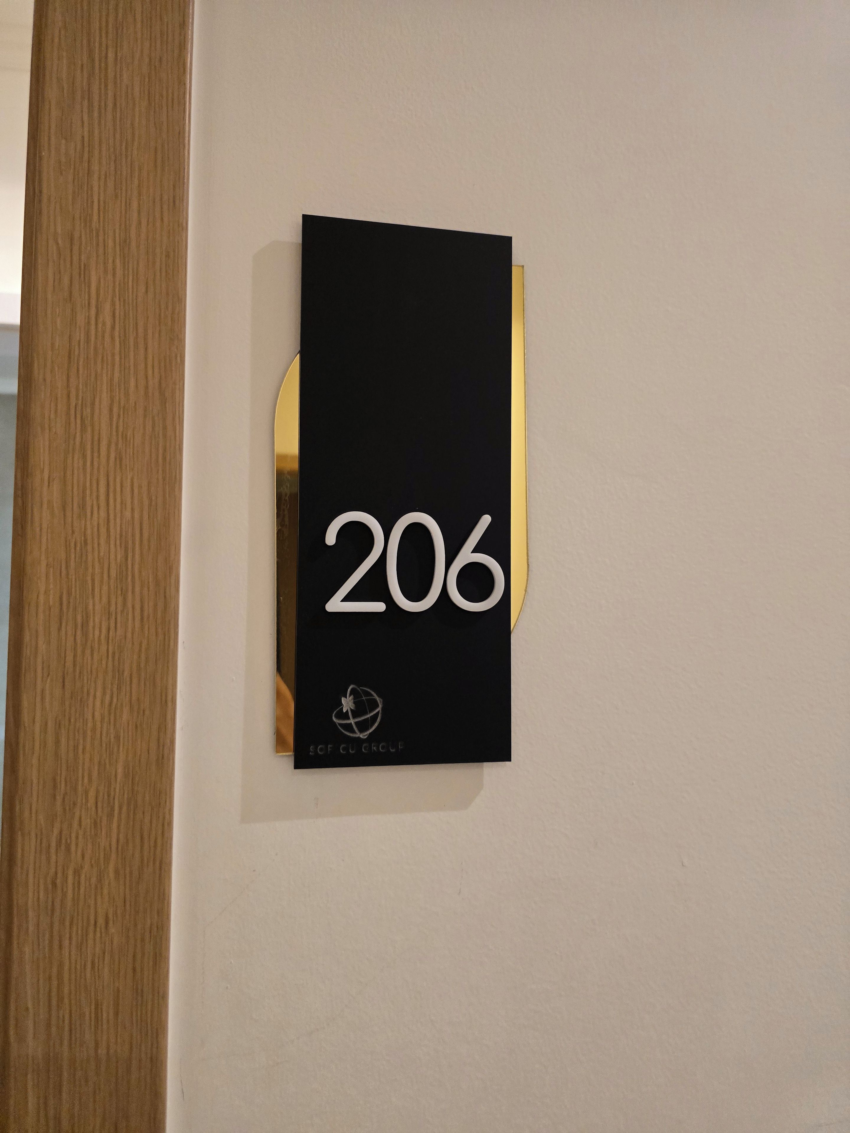 Un letrero negro con el número 206 y un logotipo en una pared blanca.