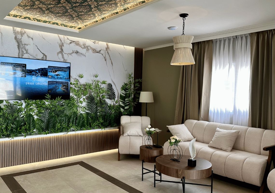 Una sala de estar moderna con un sofá, una mesa de centro, un televisor montado en una pared de mármol y una pared cubierta de plantas.