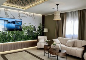 Un salon moderne avec un canapé, une table basse, un téléviseur fixé sur un mur en marbre et un mur végétal.