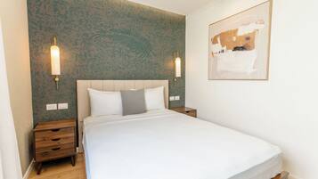 A hotel room with a bed, nightstands, a wall-mounted light fixture, and a painting.