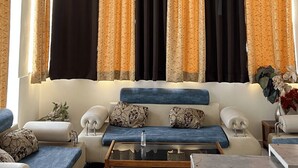 A living room with a sofa, a coffee table, and a chandelier. - Hotel Shimla Grand (Lucknow)
